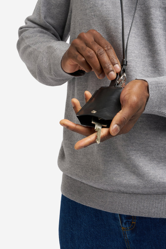 Men's accessories, key chain, black vegetable-tanned leather, clean design, holding a key.