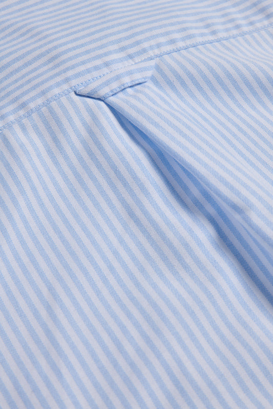 Unisex long-sleeved shirt, organic cotton, fine blue and white stripes, close-up of fabric and pleat detail.