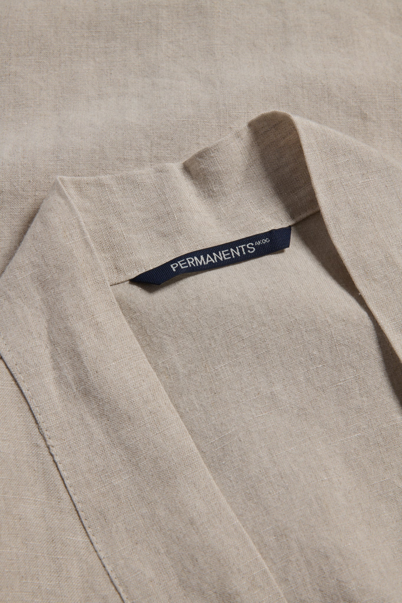 Unisex outerwear bathrobe, 100% Belgian flax linen, natural beige, with a dark blue "PERMANENTS" brand label.