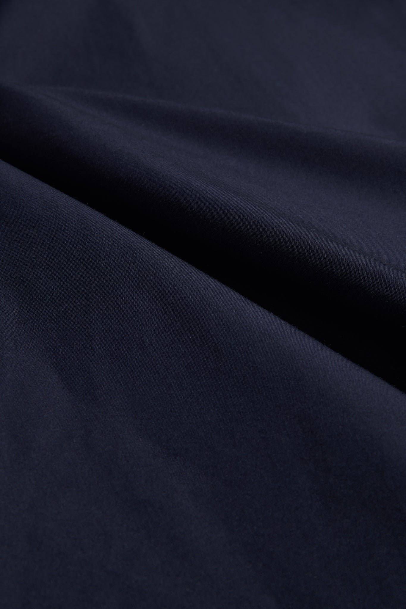 Navy organic Swiss EtaProof® cotton fabric, densely woven and waterproof, with soft folds.