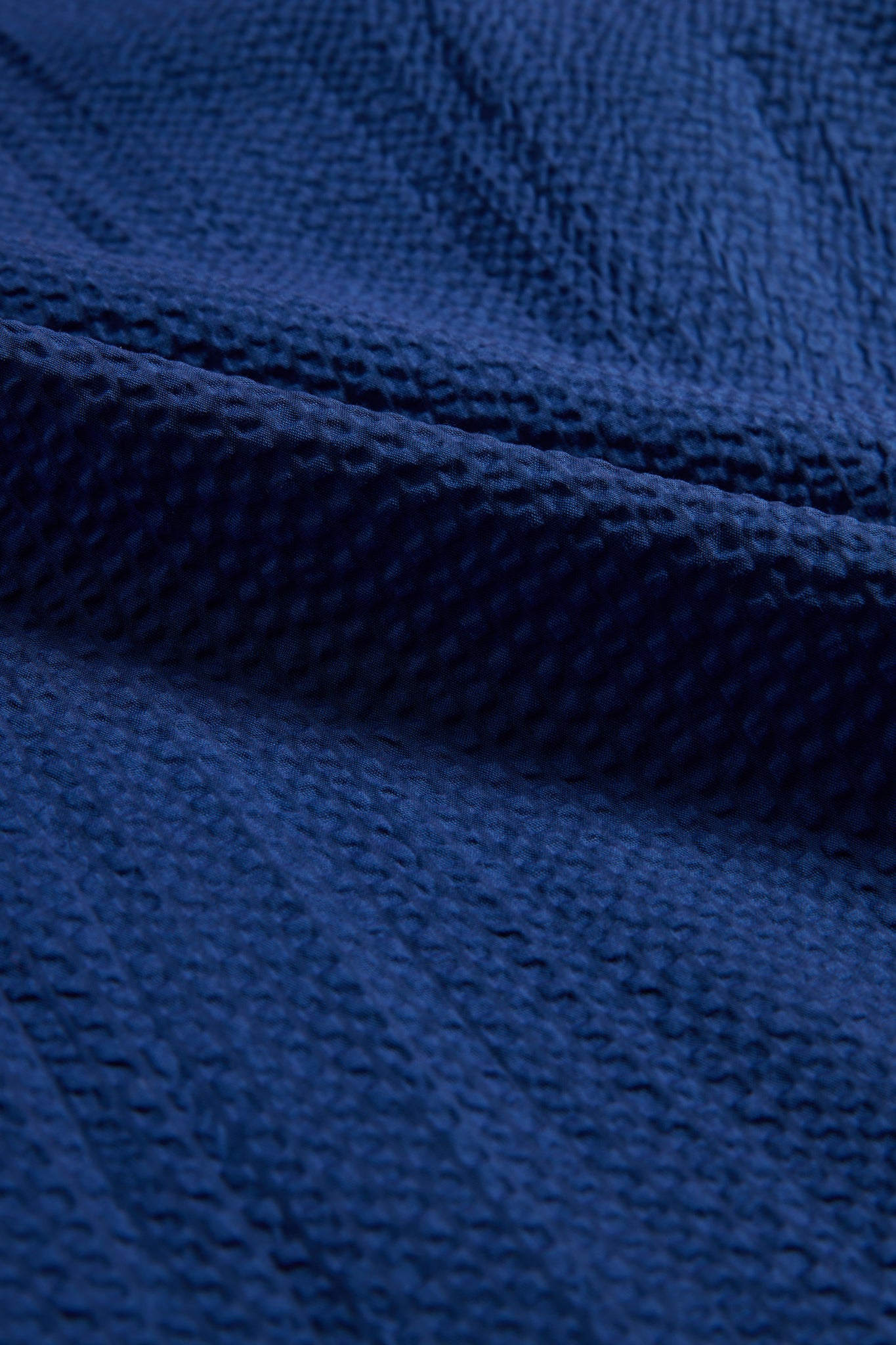 Unisex pyjama set, organic cotton seersucker, blue hour, close-up of textured fabric.