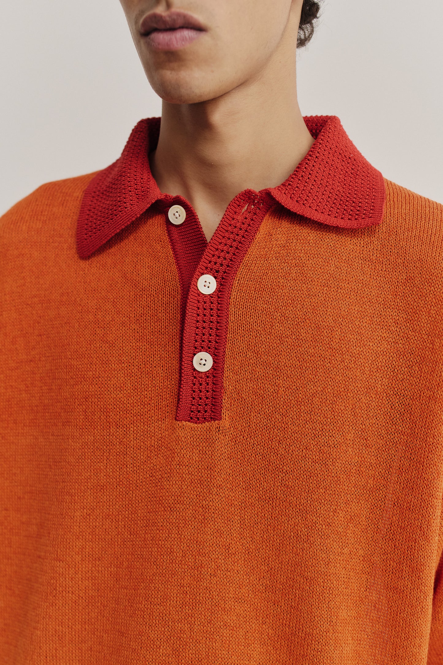 Men's knit short-sleeved polo, linen-organic cotton blend, orange with contrasting red spread collar and placket.