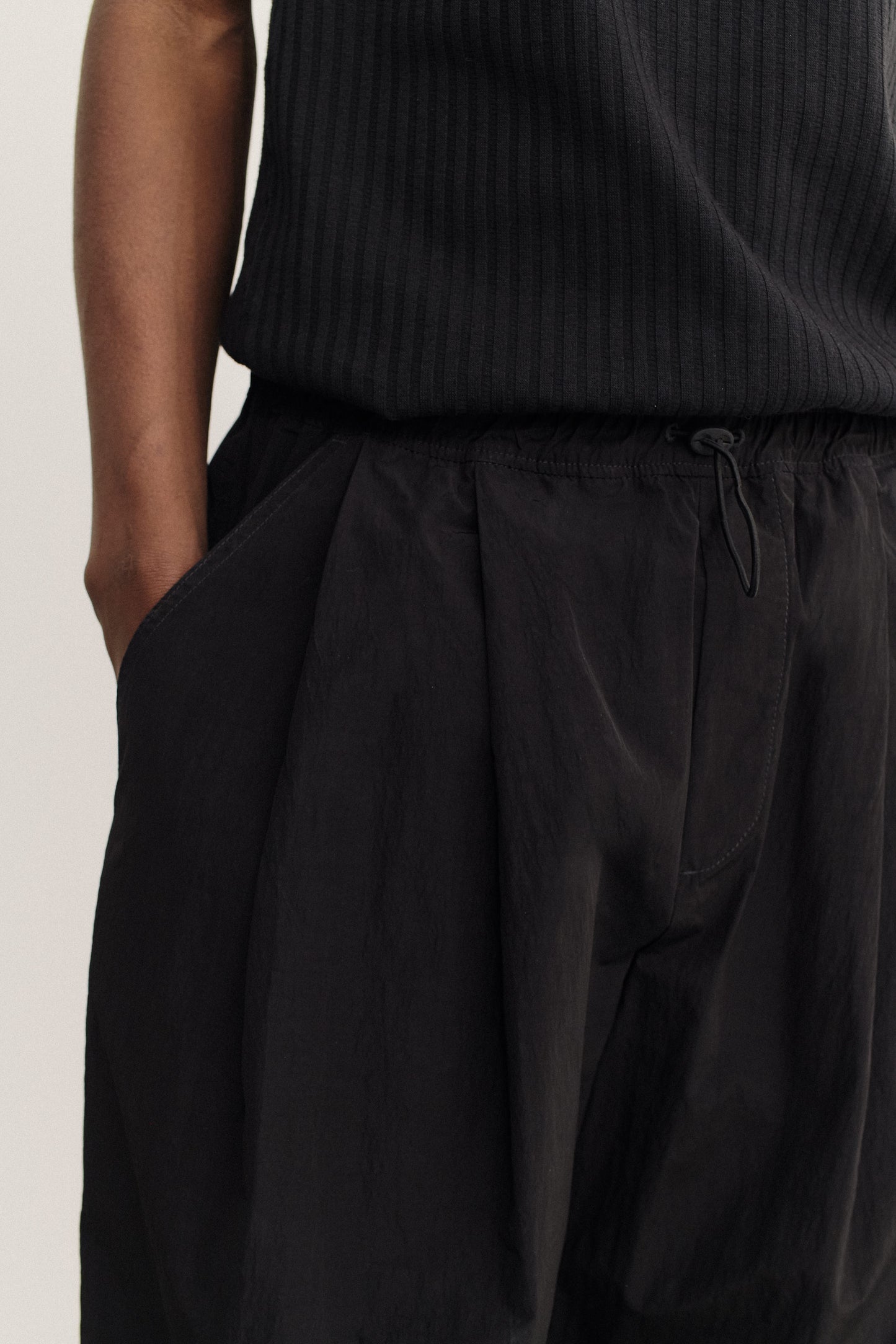 Men's long-pants, recycled nylon and cotton blend, water-repellent, black, with elastic waist and slanted pockets.