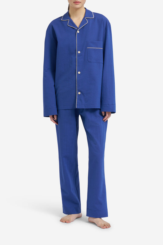 Women's long-sleeved shirt and long-pants pyjama set in blue hour organic cotton seersucker with piped trim.
