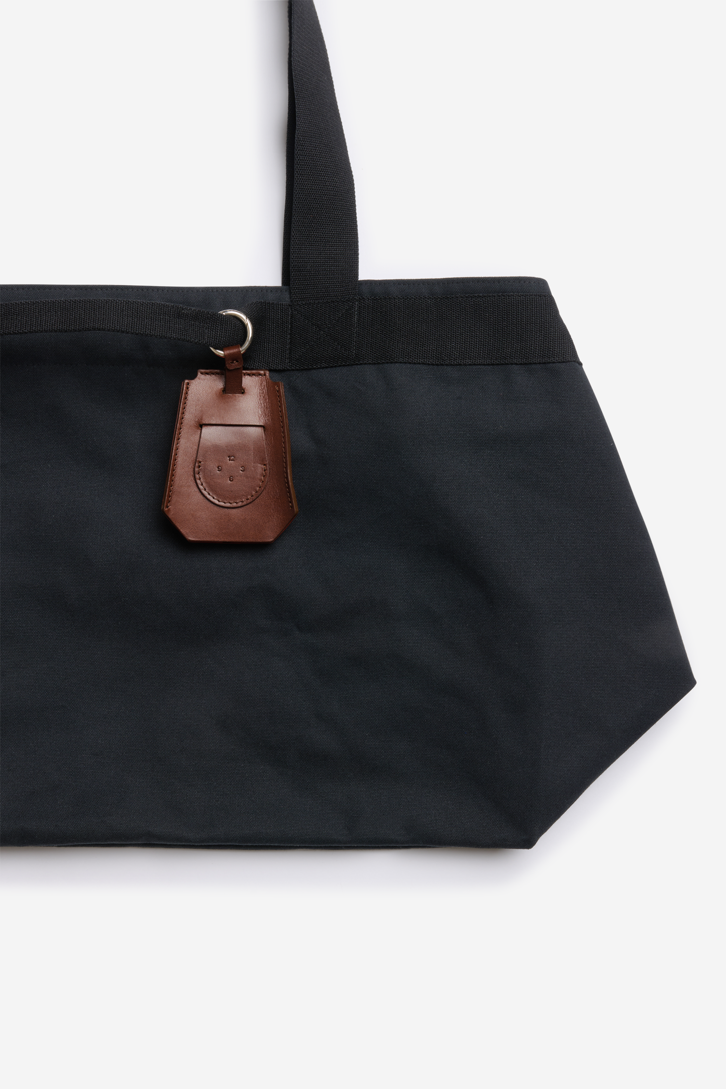 Accessories key chain, vegetable-tanned leather, brown, attached to a black tote bag.