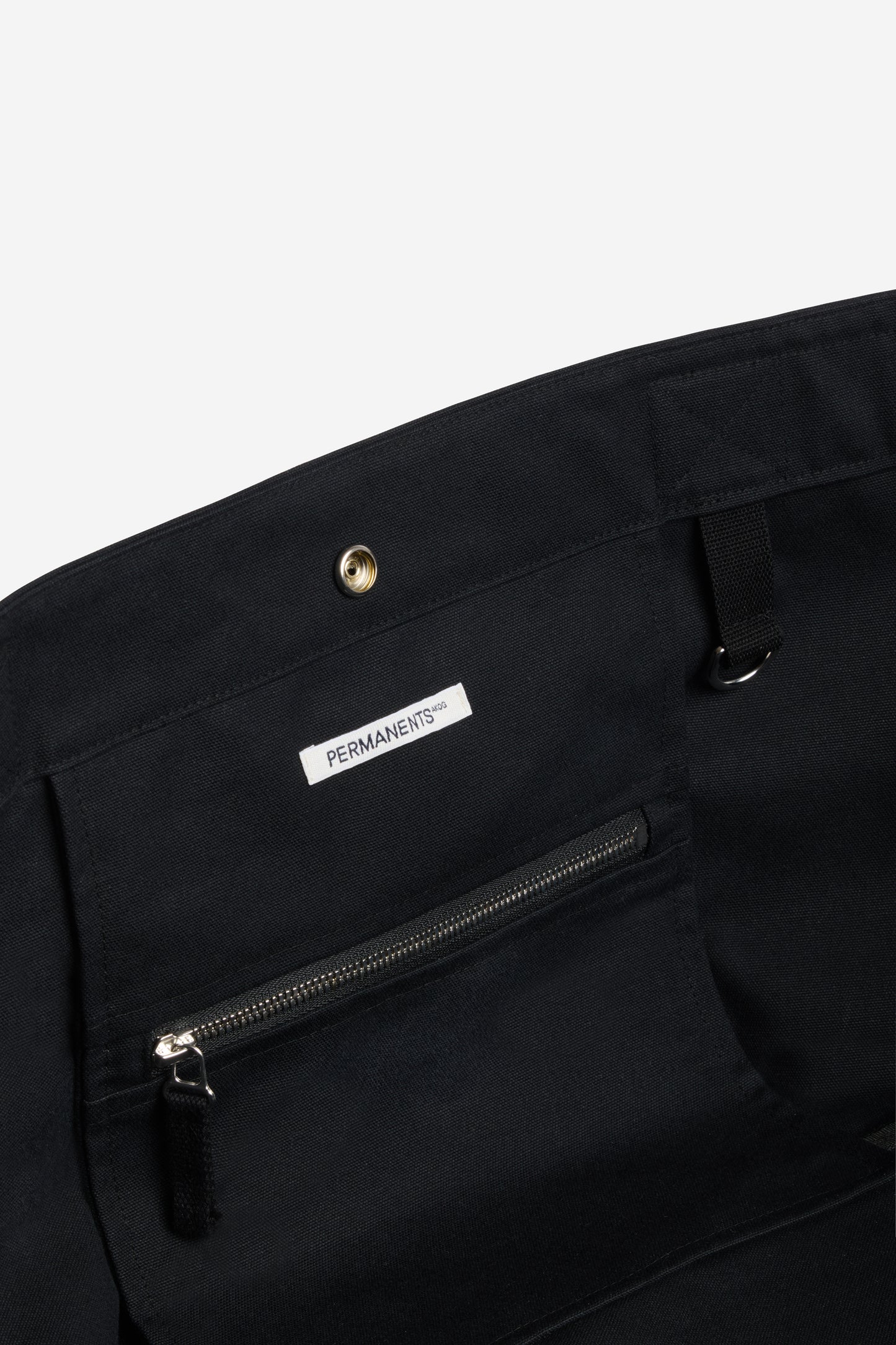 Accessories carryall bag, black recycled Ventile cotton, with interior zip pocket and "PERMANENTS" label.