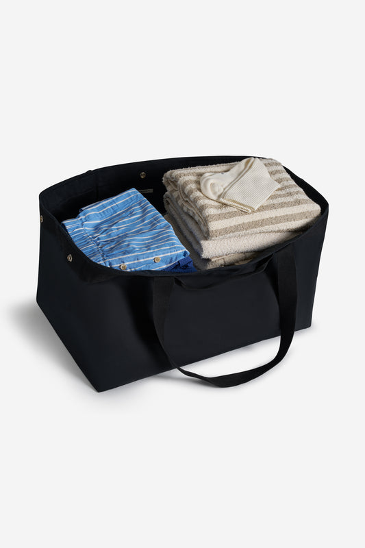 Accessories carryall bag, recycled Ventile cotton, black, with two handle lengths, filled with folded clothes.