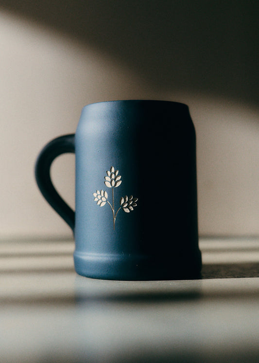 Stoneware beer mug, dark blue with engraved hop plant details.