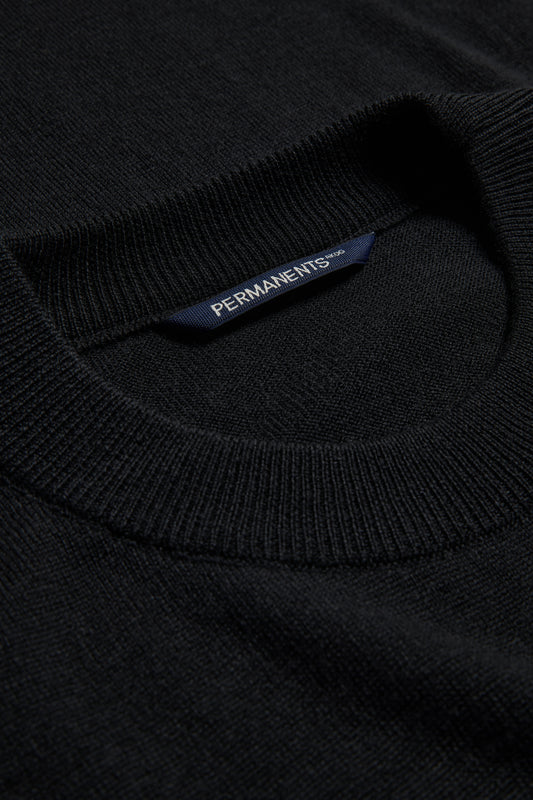 Unisex knit crewneck, black mulesing-free merino wool, with ribbed neck and PERMANENTS® label.