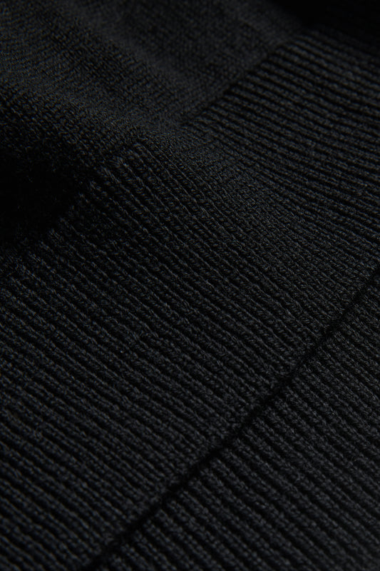 Unisex knit crewneck, black mulesing-free merino wool, close-up of fine rib-knit texture.