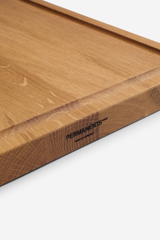 Oak chopping board with juice groove, "PERMANENTS" logo, and "MADE IN GERMANY" inscription.