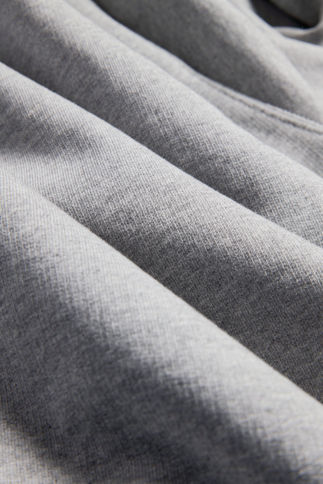 Unisex jersey hoodie, grey melange, 100% organic cotton, pre-washed, close-up of fabric texture.