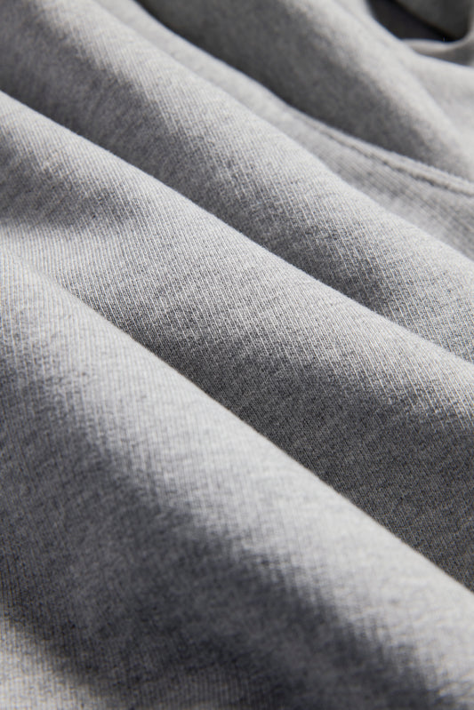 Unisex jersey hoodie, grey melange, 100% organic cotton, pre-washed, close-up of fabric texture.