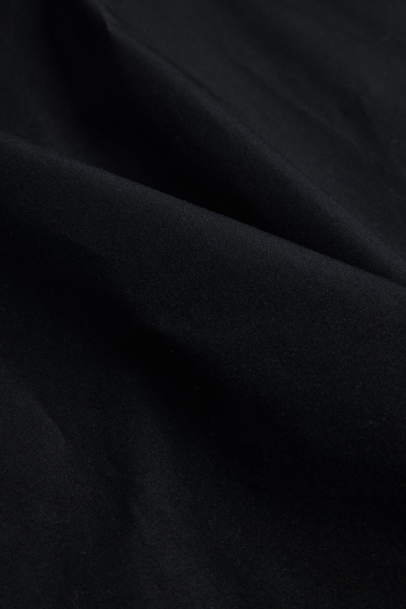 Black organic cotton EtaProof® fabric, dense and waterproof, with subtle folds.