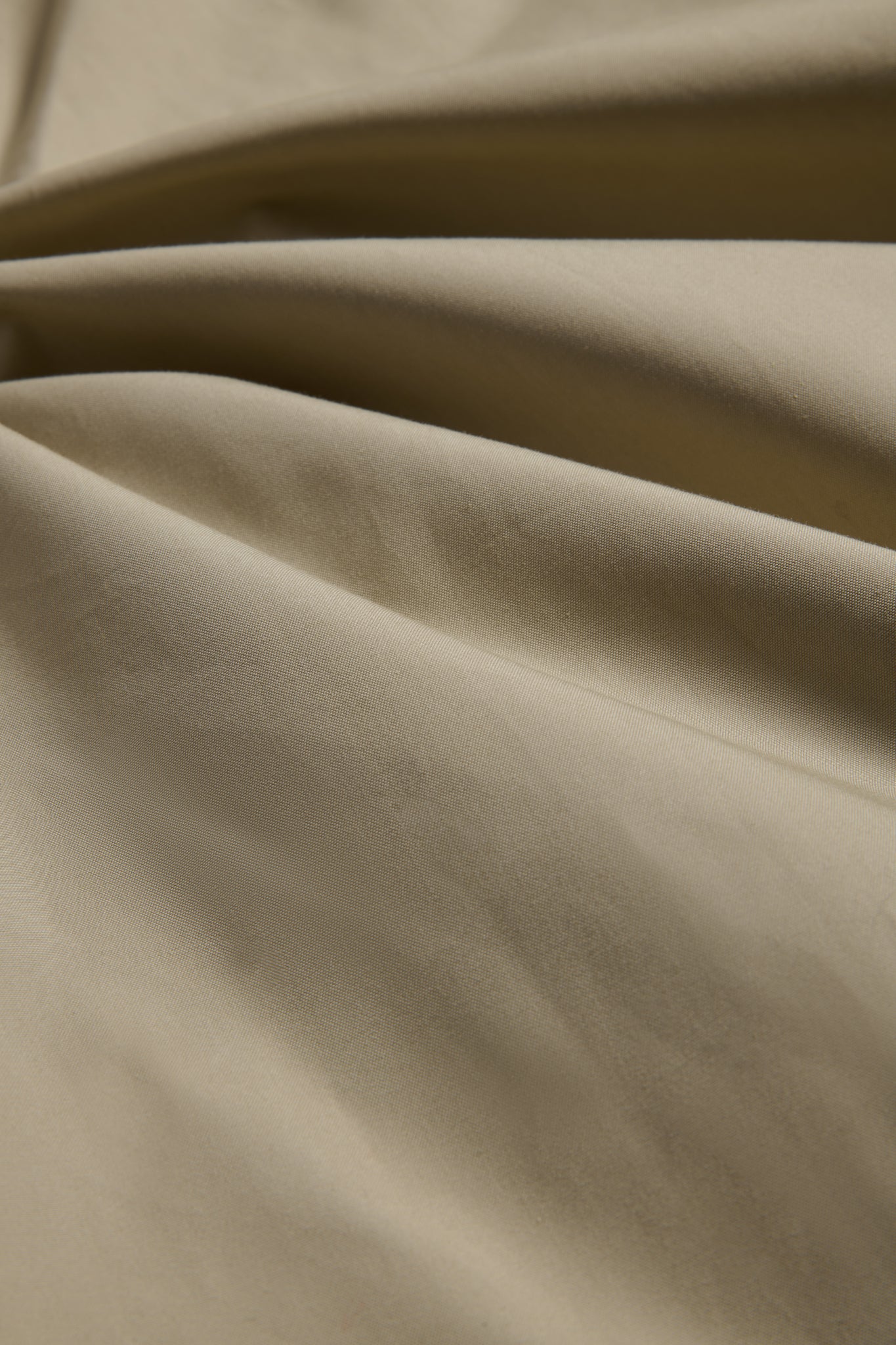 Outerwear parka, stone organic cotton EtaProof® fabric, showing dense weave and subtle folds.