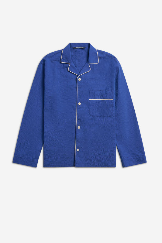 Unisex long-sleeved pyjama shirt, blue organic cotton seersucker with white piped trim and buttons.