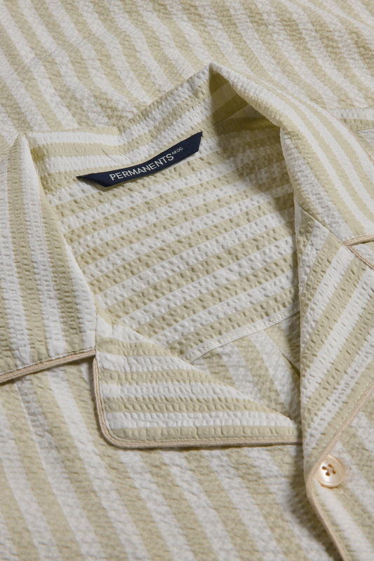 Unisex pyjama set, organic cotton seersucker, sage stripe, piped trim, close-up of collar and button.