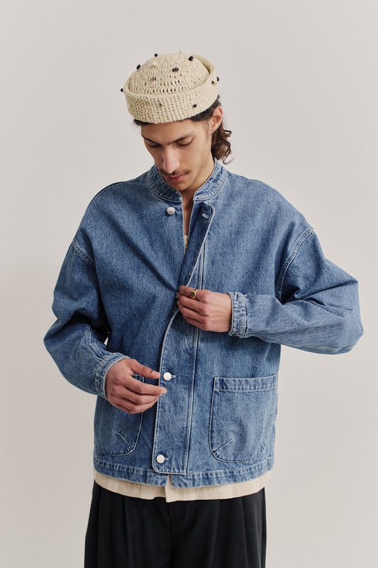 Men's outerwear denim jacket, stone washed indigo, with stand-up collar, patch pockets, and buttoned cuffs.