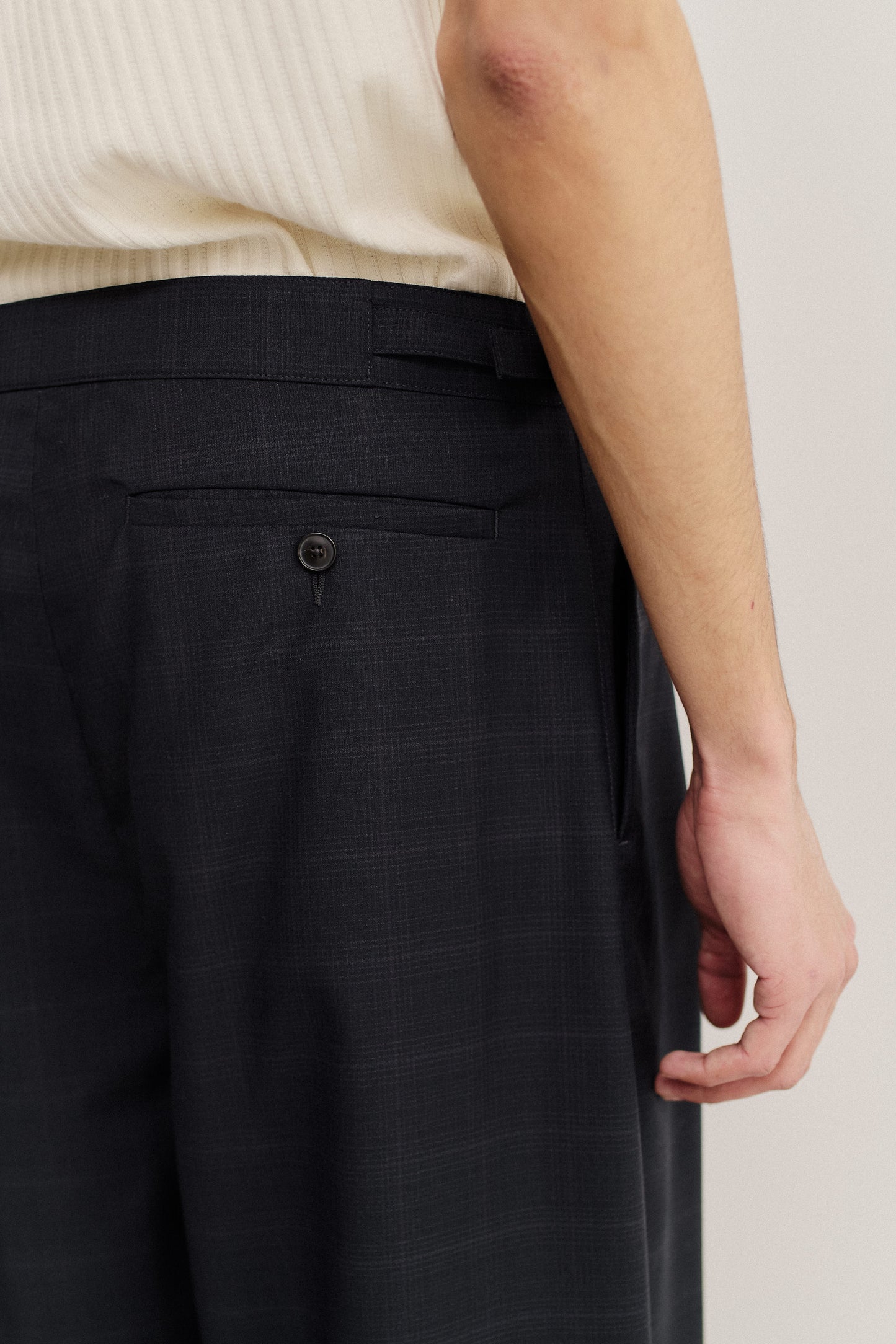 Men's long pants, virgin wool with subtle checkered pattern, dark grey, back welt pocket with button.