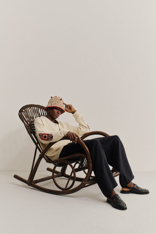Men's knit cardigan, cotton-cashmere blend, cream with embroidered elbows, worn with navy pants.