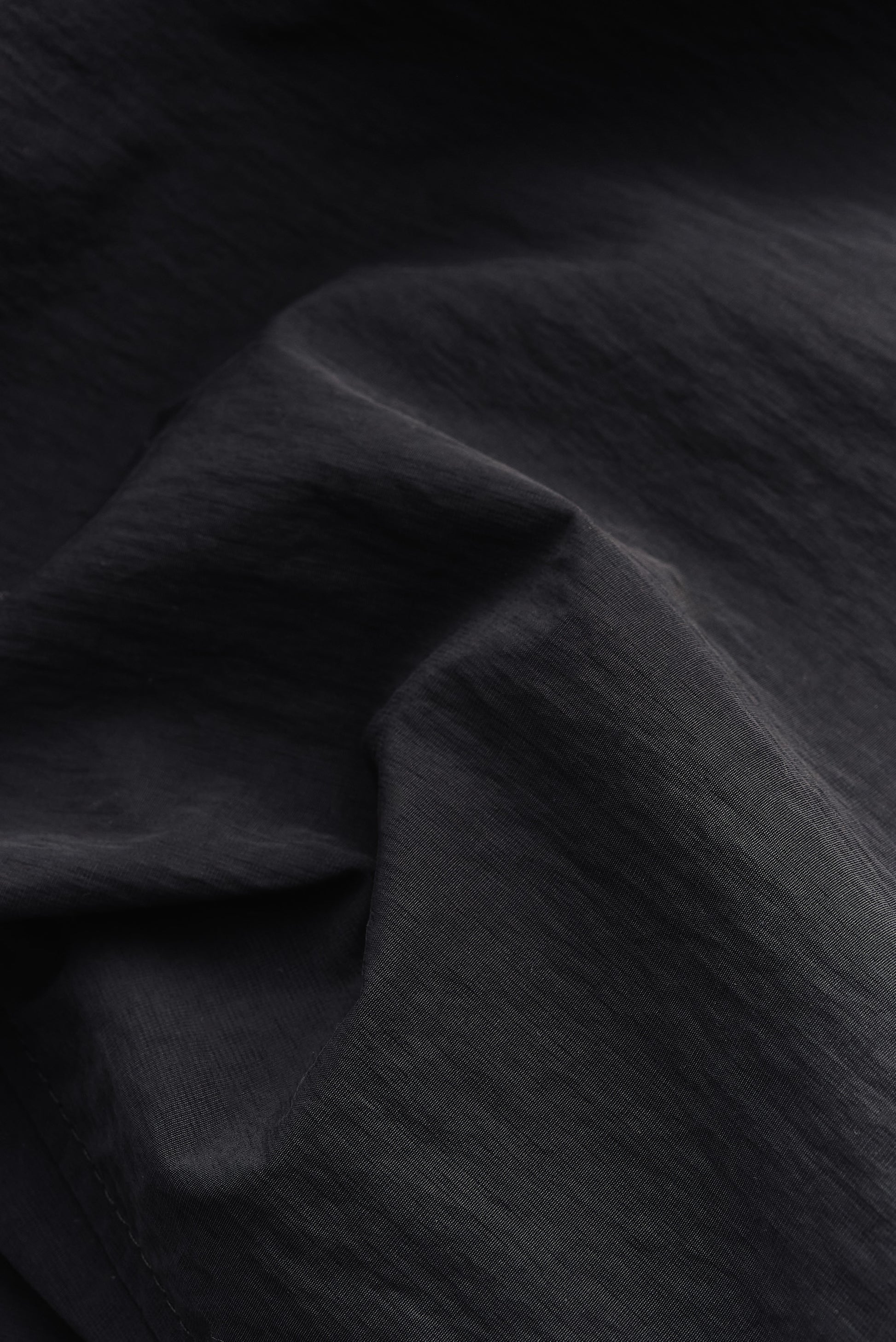 Men's outerwear, black recycled nylon and cotton blend, water-repellent fabric with subtle texture.