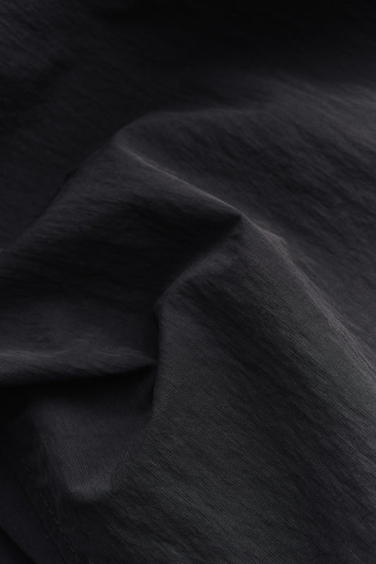 Men's outerwear, black recycled nylon and cotton blend, water-repellent fabric with subtle texture.