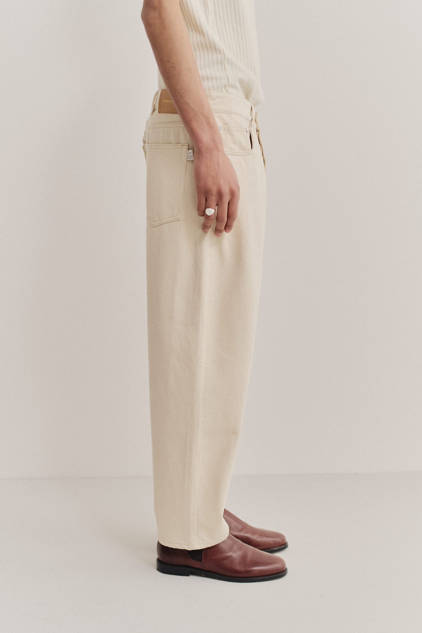 Men's long-pants, organic cotton raw denim, off-white, loose fit, tapered leg, cropped length.
