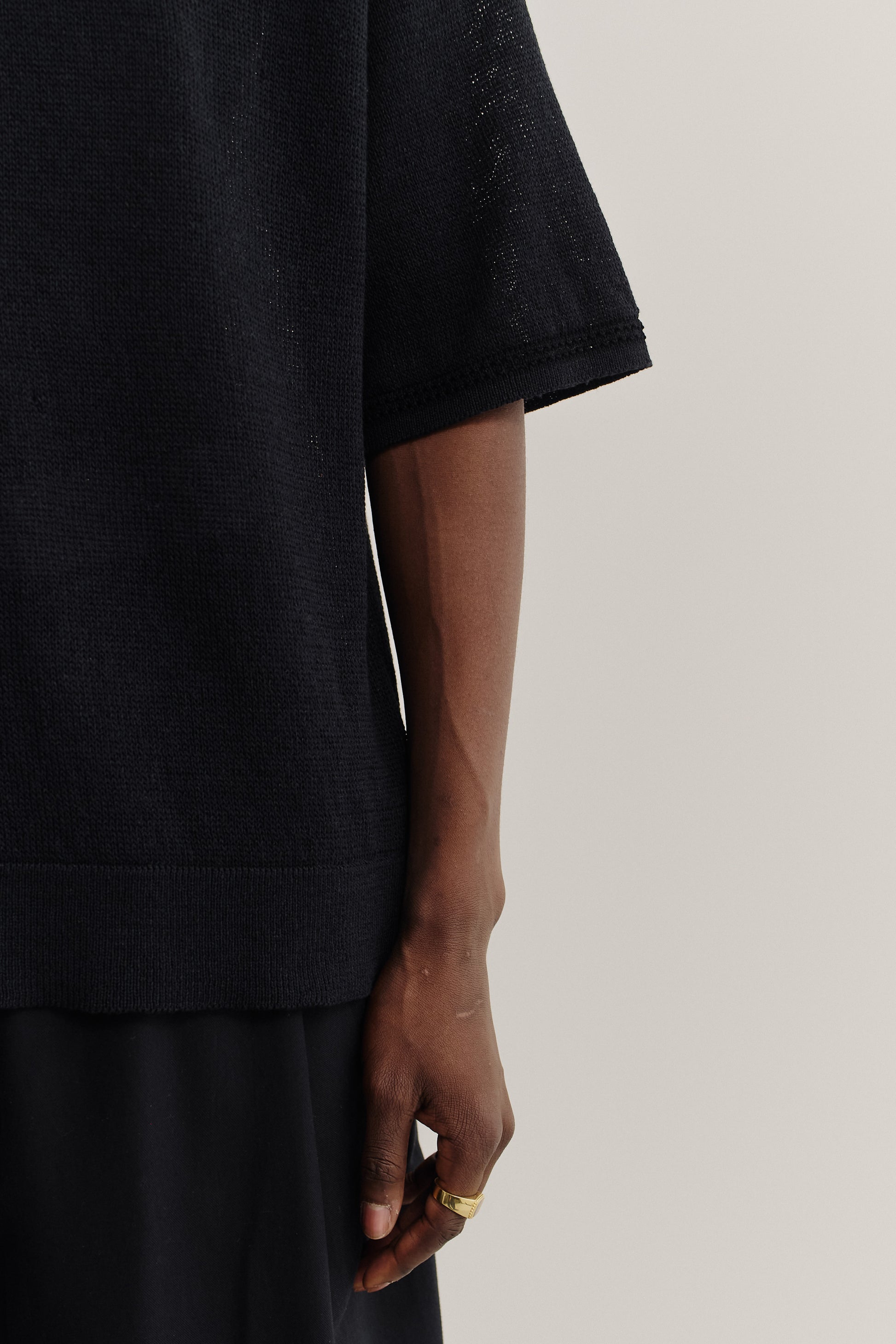 Men's knit short-sleeved polo, linen-organic cotton blend, black, with contrasting collar and sleeve stripe.