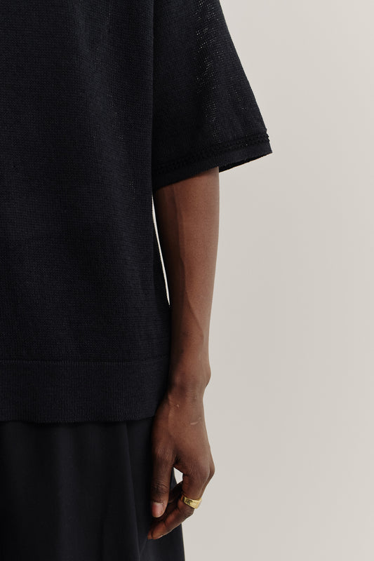 Men's knit short-sleeved polo, linen-organic cotton blend, black, with contrasting collar and sleeve stripe.