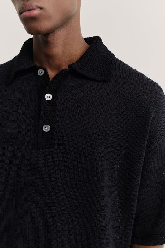 Men's knit short-sleeved polo, black linen-organic cotton blend, with spread collar and button placket.