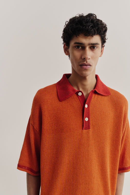 Men's knit short-sleeved polo, linen-organic cotton blend, orange with red contrast collar and sleeve stripe.