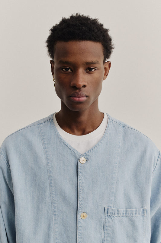 Men's long-sleeved overshirt, light blue organic cotton-silk denim with v-neck, dropped shoulder, and patch pockets.