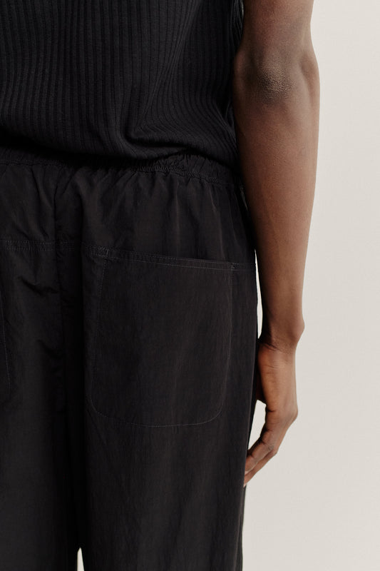 Men's long pants, recycled nylon and cotton blend, water-repellent, black, with elastic waist and back pockets.