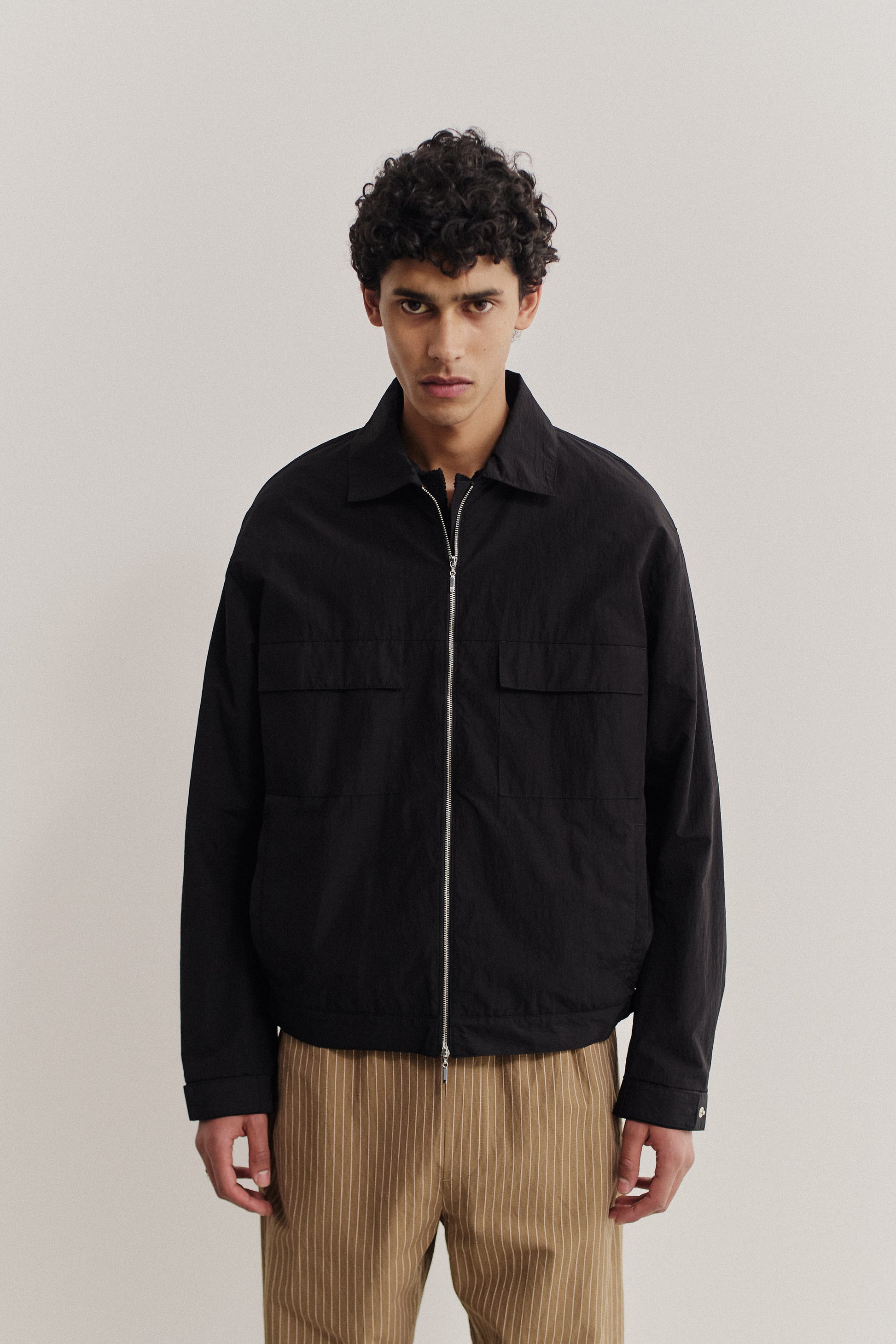 Men's outerwear jacket, black recycled nylon cotton blend, boxy silhouette, flap chest pockets, front zip.