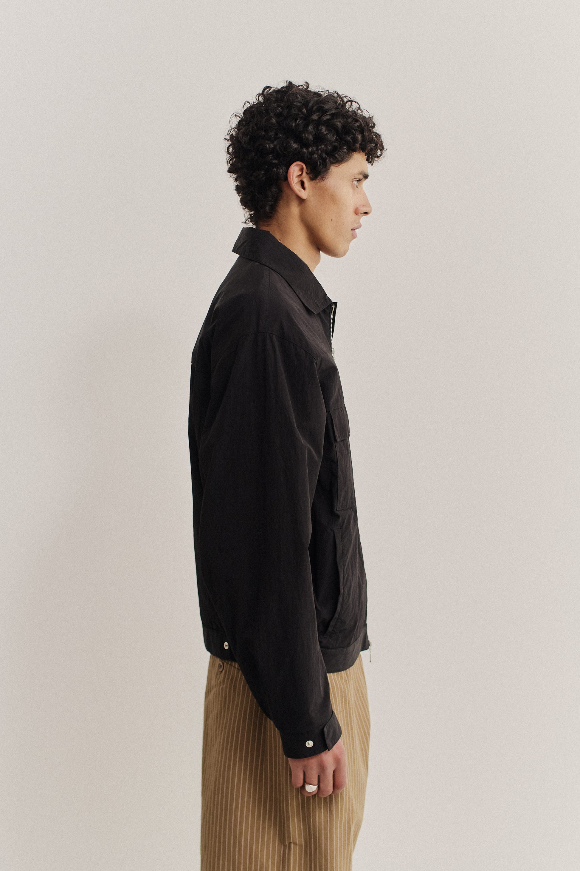 Men's outerwear jacket, black recycled nylon cotton blend, boxy silhouette, flap chest pockets, elasticated waist.