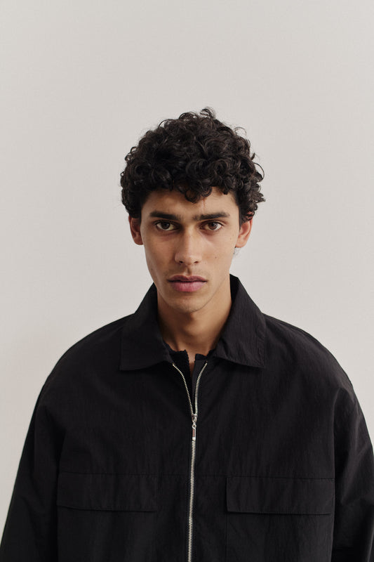 Men's outerwear jacket, recycled nylon cotton blend, black, with front zip and flap chest pockets.