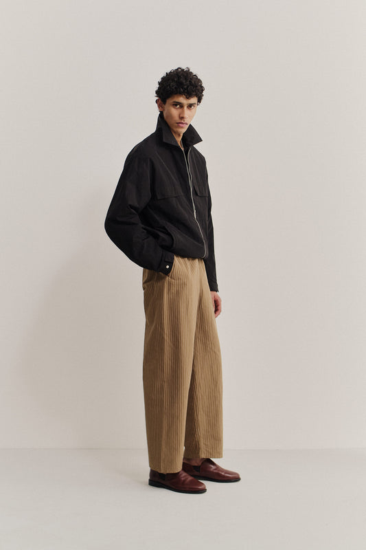 Men's outerwear jacket, black recycled nylon-cotton blend, with flap chest pockets, elasticated waist, and front zip.