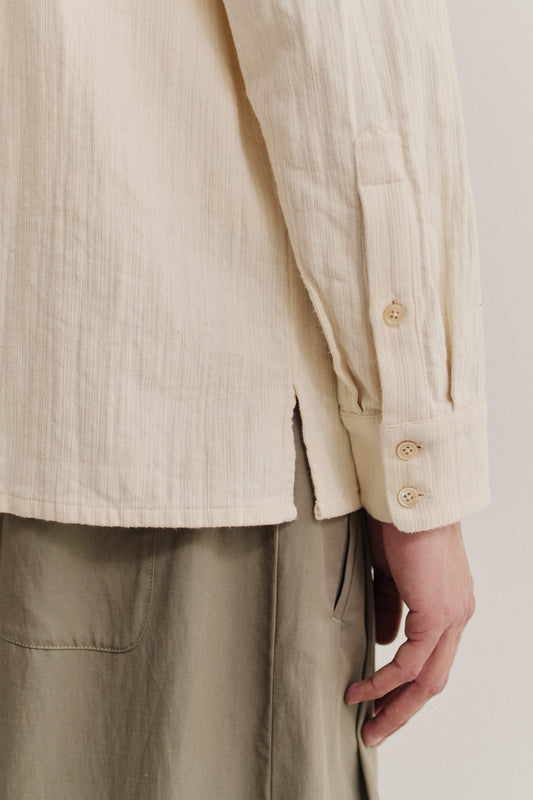 Men's long-sleeved shirt, recycled cotton mix, textured weave, off-white, with buttoned cuffs and side slit.