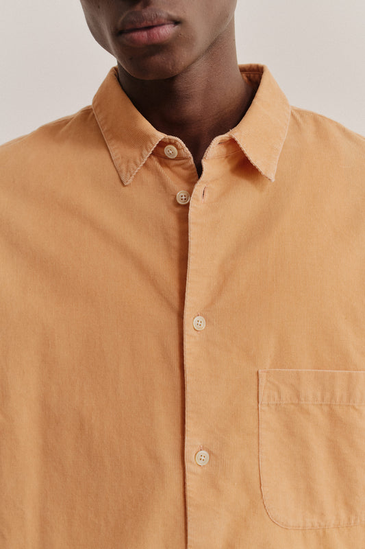 Men's long-sleeved shirt, 100% cotton light corduroy, garment washed, in a warm orange hue, with a regular collar and front patch pocket.