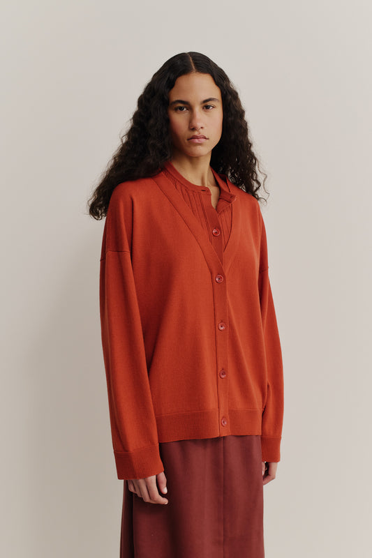 Women's knit cardigan, 100% merino wool, brick red, with a deep V-neck and mock underlayer.