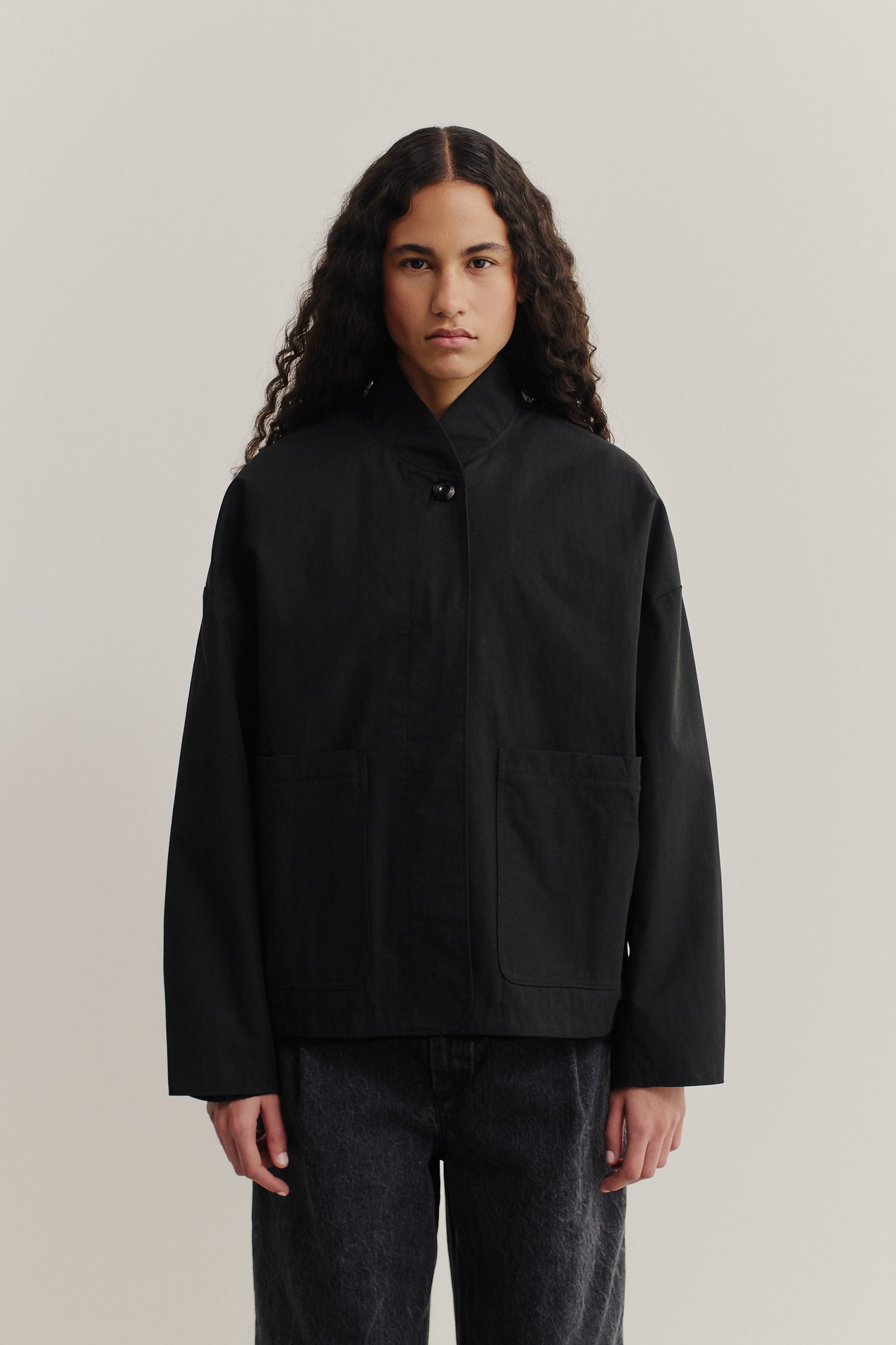 Women's outerwear jacket, black water-repellent cotton blend, with stand collar and front patch pockets.