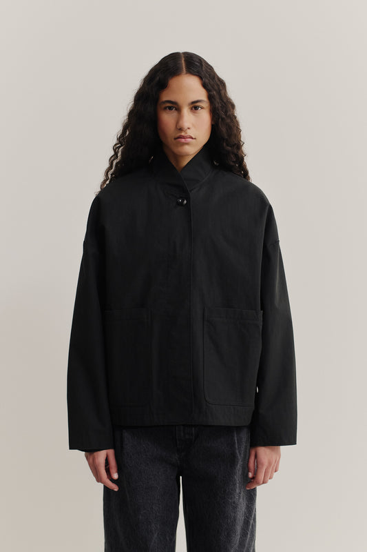 Women's outerwear jacket, black water-repellent cotton blend, with stand collar and front patch pockets.