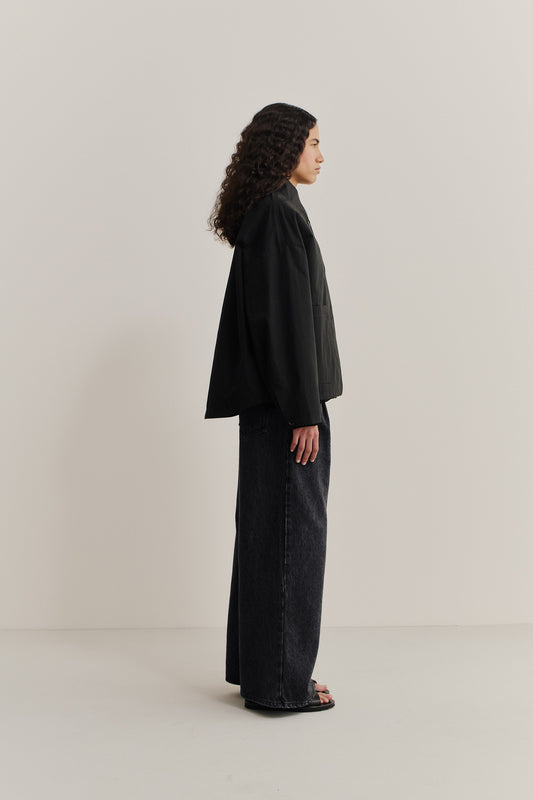 Women's outerwear jacket, black water-repellent cotton blend, wide-cut silhouette, stand collar, and front patch pockets.