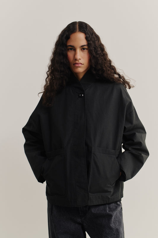 Women's outerwear jacket, black water-repellent cotton blend, with stand collar and front patch pockets.