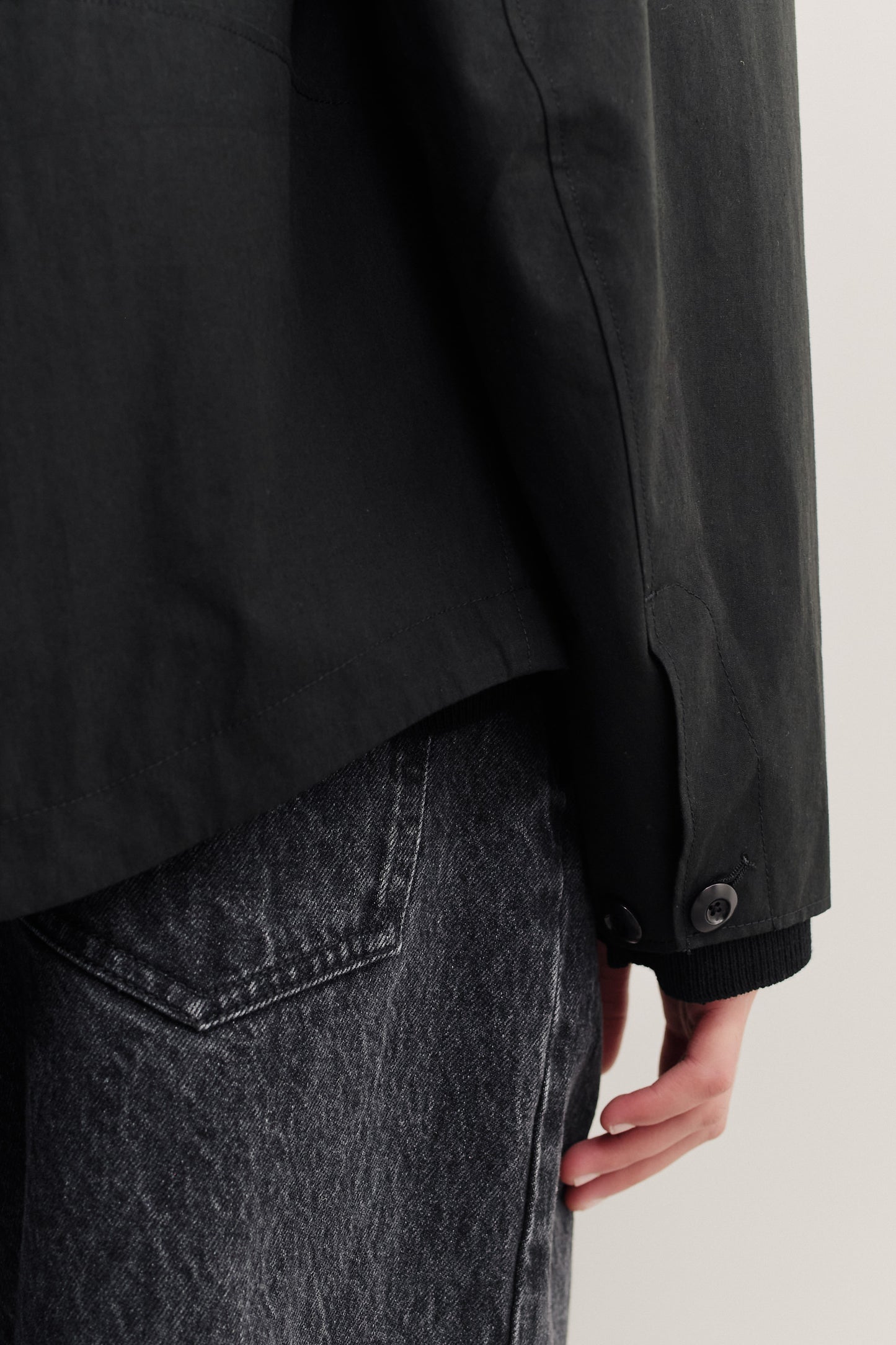 Women's outerwear jacket, black cotton blend, with a wide silhouette and buttoned sleeve hem, paired with dark denim.