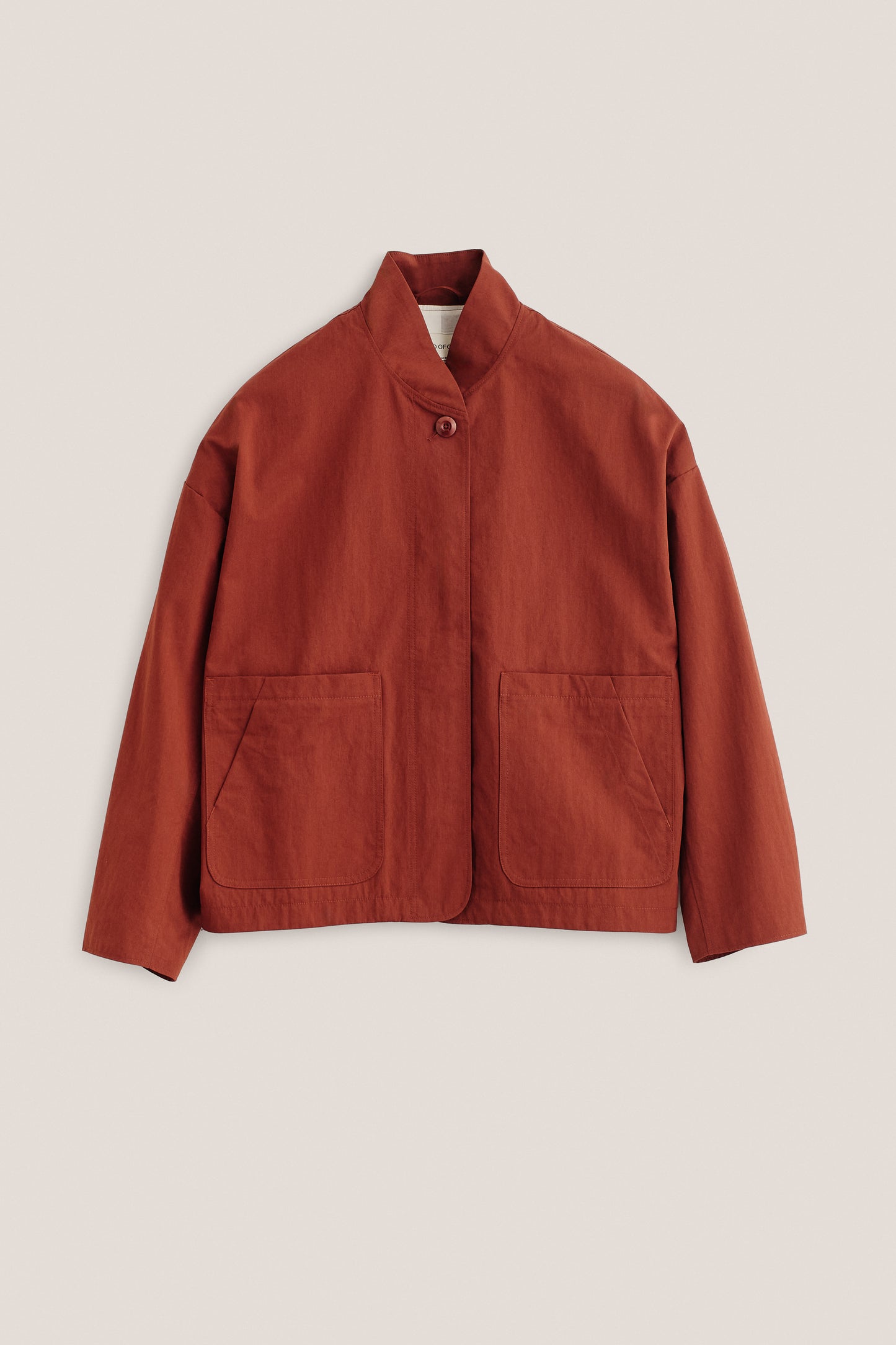 Women's outerwear jacket, cotton blend, rust-colored, with stand collar, single visible button, and front patch pockets.
