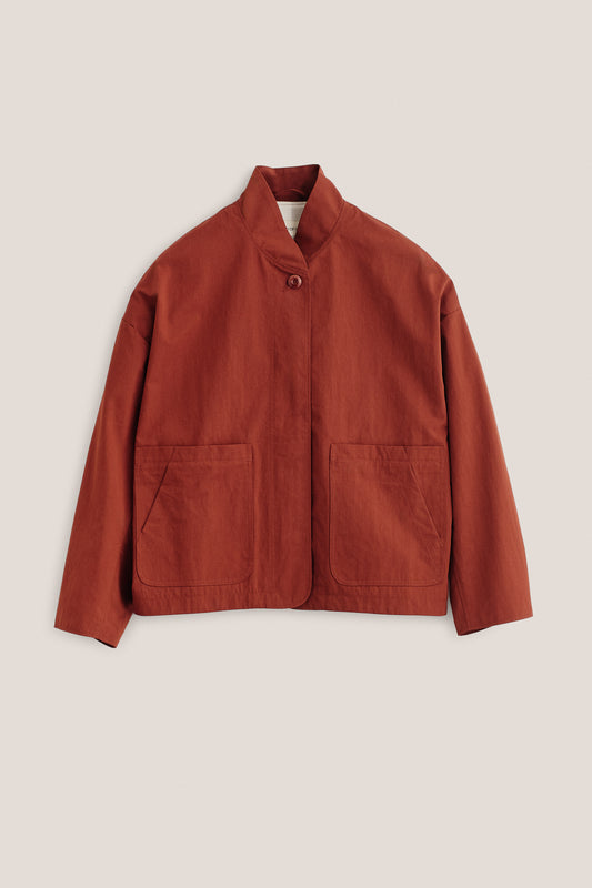 Women's outerwear jacket, cotton blend, rust-colored, with stand collar, single visible button, and front patch pockets.