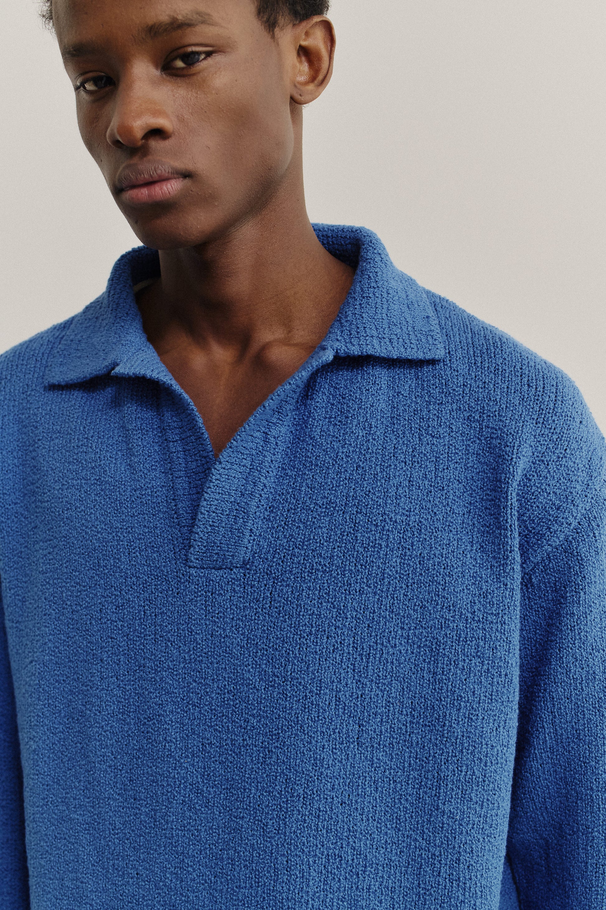 Men's knit long-sleeved polo, organic cotton bouclé, vibrant blue, relaxed fit, open collar.