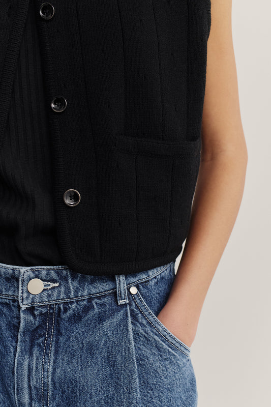 Women's knit vest, black 100% merino wool, ribbed ajour knit, button-front, with pocket, styled with blue denim.