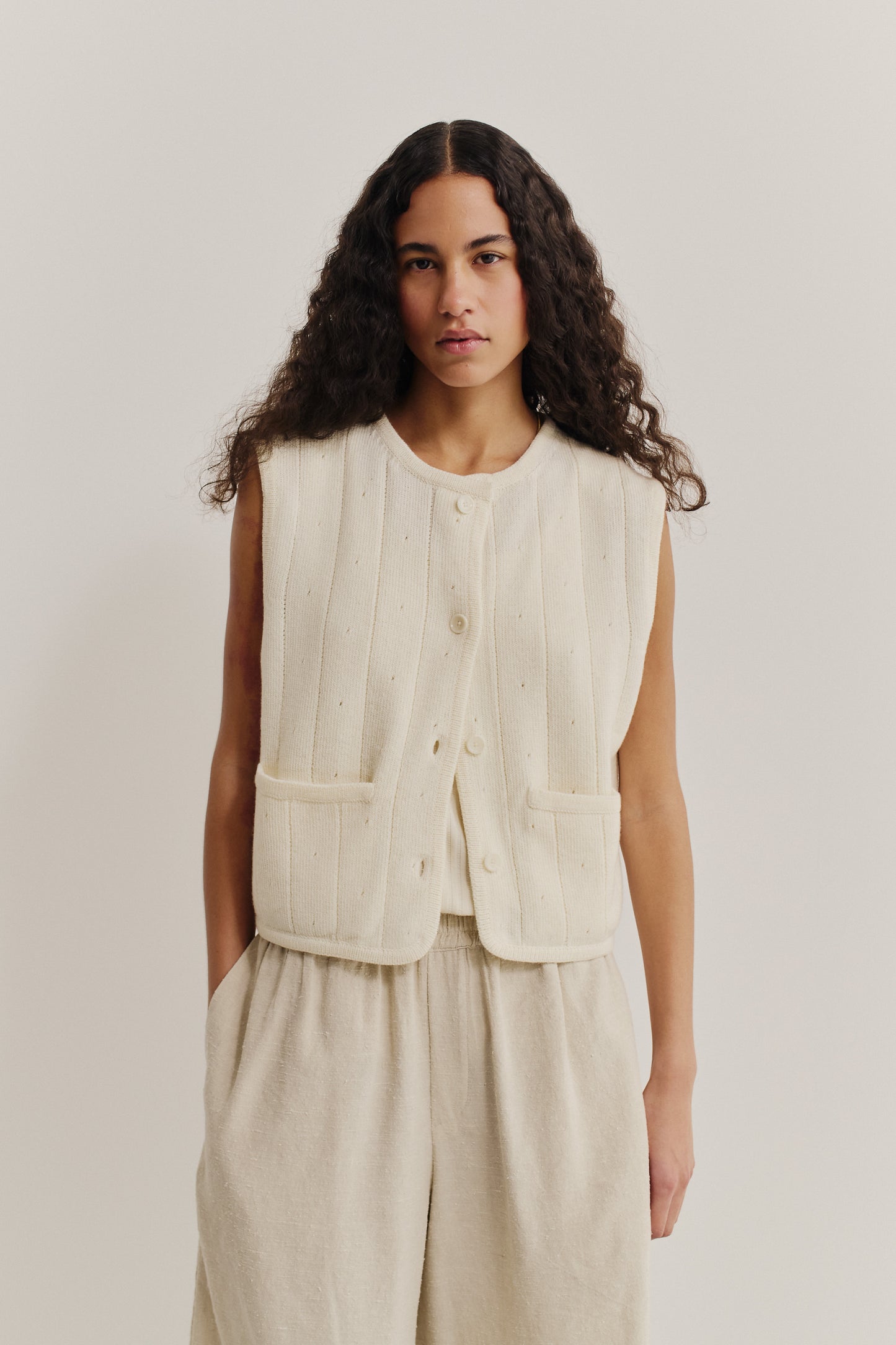 Women's knit vest, 100% merino wool, ajour knit, off-white, cropped, with front buttons and pockets.
